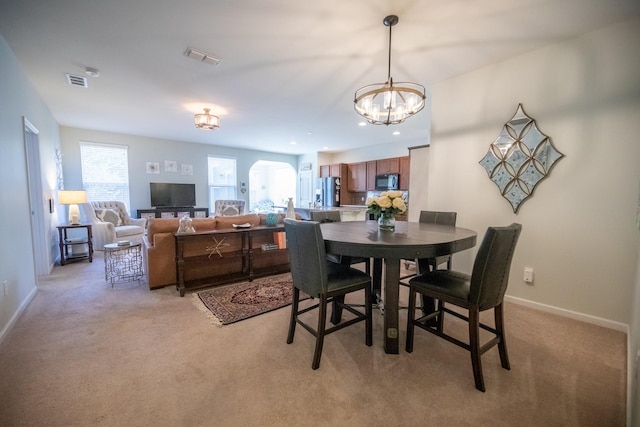 dining room featuring light colored carpet and a notable chandelier