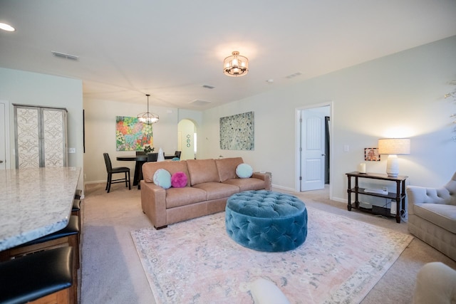 carpeted living room featuring a notable chandelier