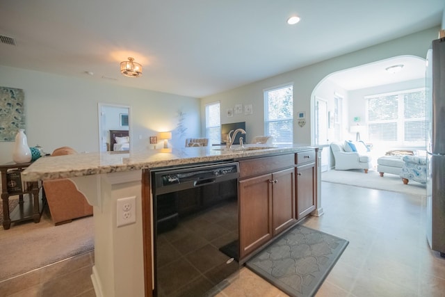 kitchen featuring dishwasher, light carpet, sink, an island with sink, and light stone counters