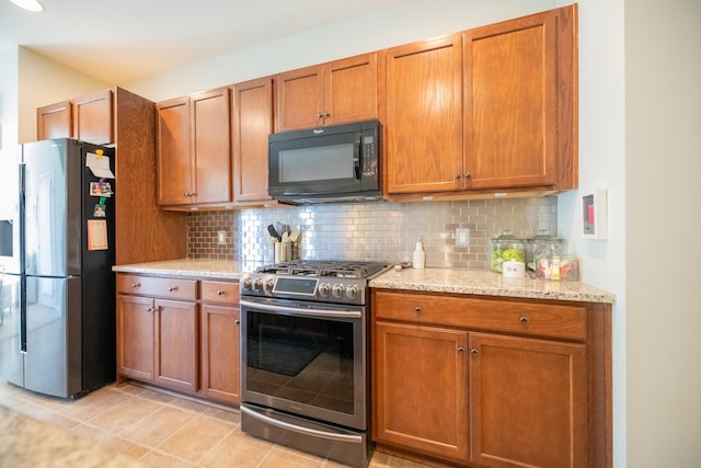 kitchen featuring stainless steel appliances, light stone counters, decorative backsplash, and light tile patterned flooring