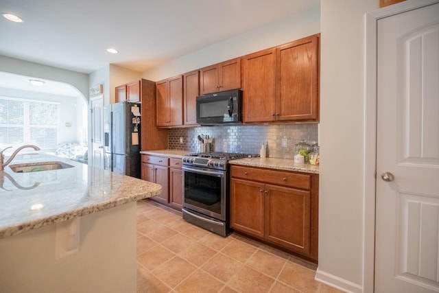 kitchen featuring sink, decorative backsplash, light stone countertops, and stainless steel appliances