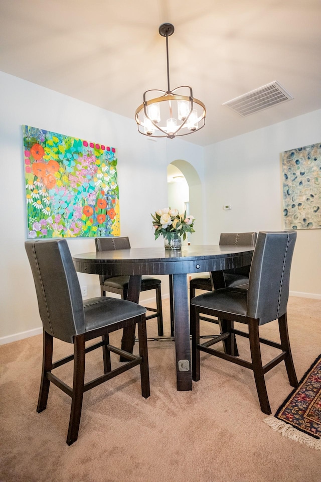 dining room with light carpet and a notable chandelier