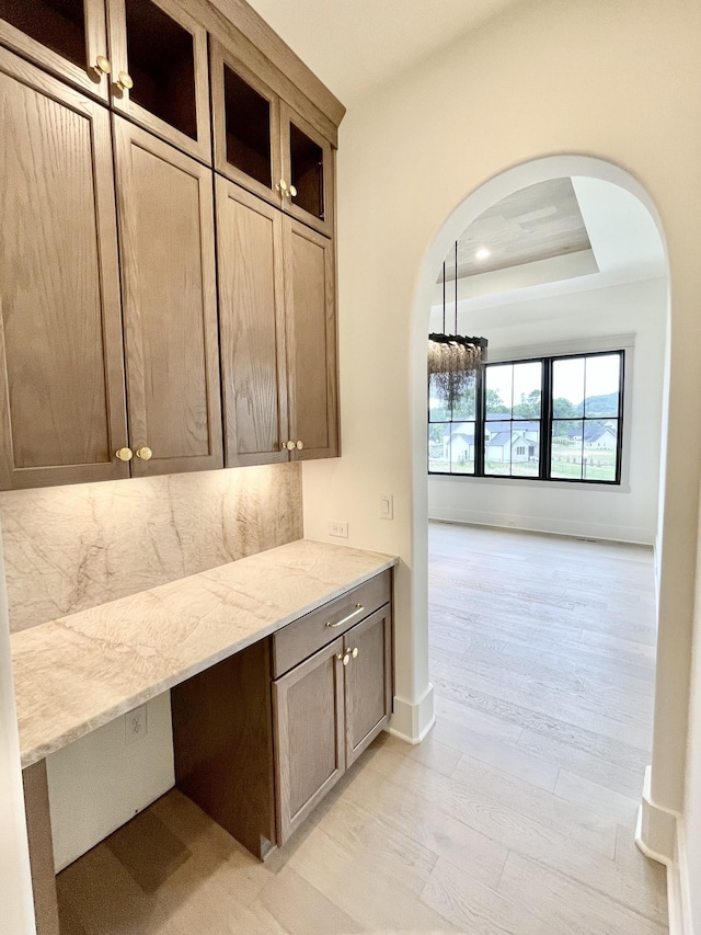 kitchen featuring light hardwood / wood-style floors, light stone counters, and a raised ceiling