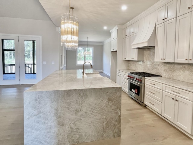 kitchen featuring custom exhaust hood, white cabinets, a spacious island, and high end stainless steel range