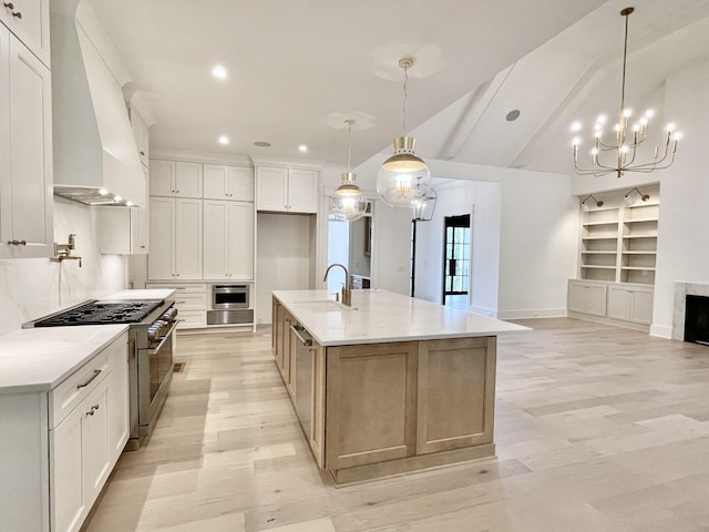 kitchen with stainless steel appliances, white cabinetry, light stone countertops, and a large island with sink