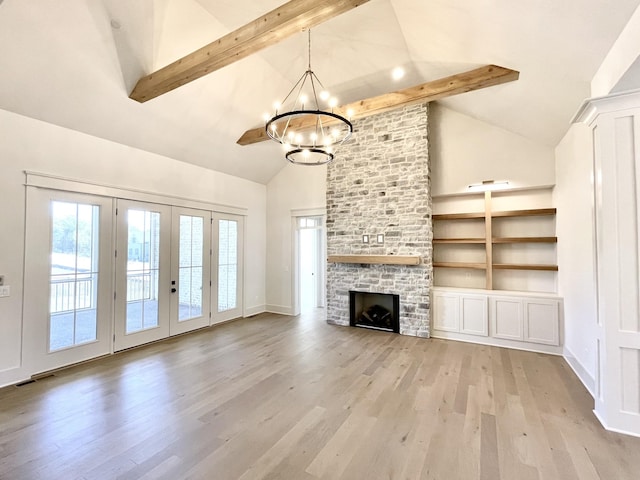 unfurnished living room featuring a stone fireplace, beamed ceiling, an inviting chandelier, built in features, and light hardwood / wood-style flooring