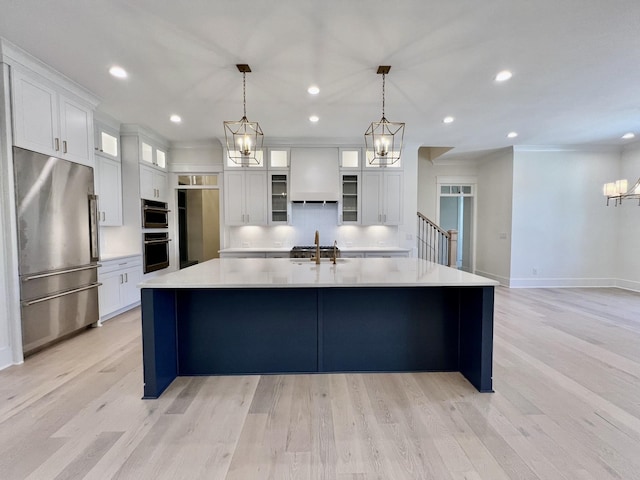 kitchen featuring white cabinets, decorative light fixtures, stainless steel refrigerator, and a spacious island