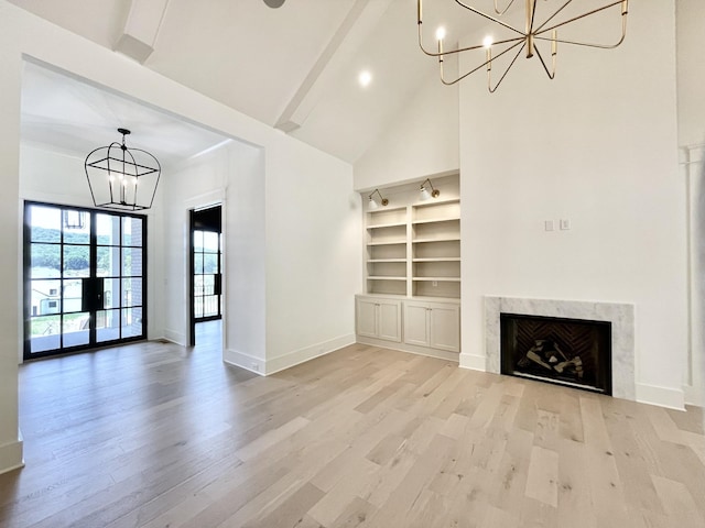 unfurnished living room featuring light hardwood / wood-style flooring, a chandelier, beam ceiling, and a fireplace