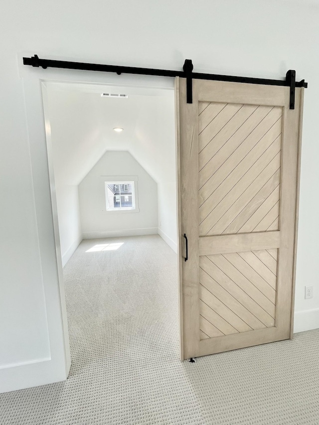 additional living space with a barn door, light colored carpet, and lofted ceiling