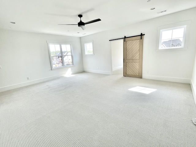 unfurnished room with light carpet, ceiling fan, and a barn door