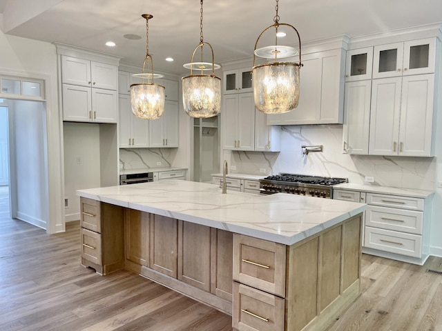 kitchen featuring light stone counters, a spacious island, pendant lighting, and white cabinets