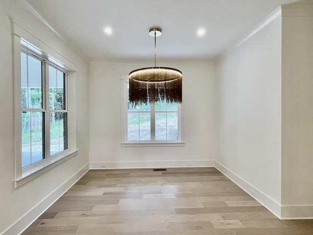 unfurnished dining area with light wood-type flooring, a wealth of natural light, and crown molding