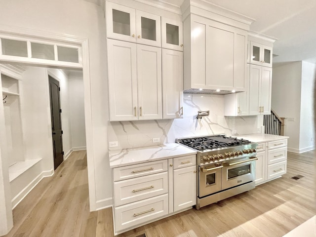 kitchen with white cabinetry, range with two ovens, decorative backsplash, light stone counters, and light hardwood / wood-style flooring