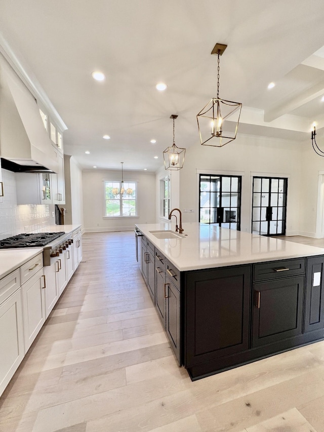 kitchen with pendant lighting, white cabinetry, sink, light wood-type flooring, and stainless steel gas stovetop