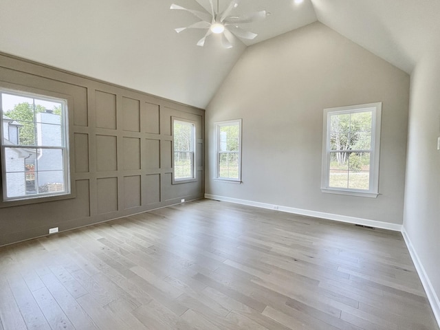 spare room with ceiling fan, light hardwood / wood-style flooring, a skylight, and high vaulted ceiling