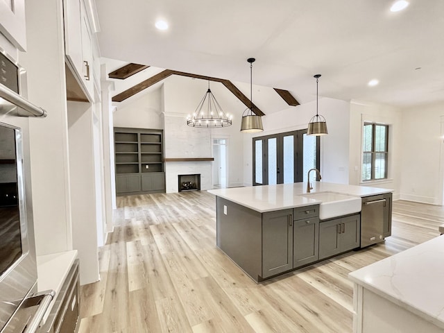 kitchen with decorative light fixtures, vaulted ceiling with beams, and an island with sink