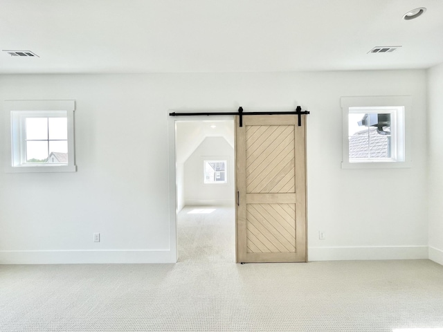 spare room featuring light carpet and a barn door