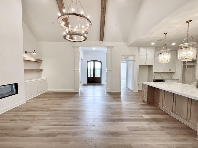 kitchen featuring a notable chandelier, white cabinetry, light stone countertops, and pendant lighting