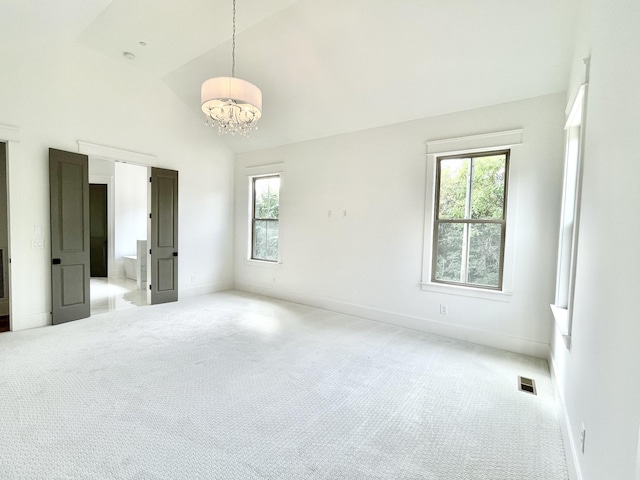 unfurnished bedroom with an inviting chandelier, high vaulted ceiling, and carpet