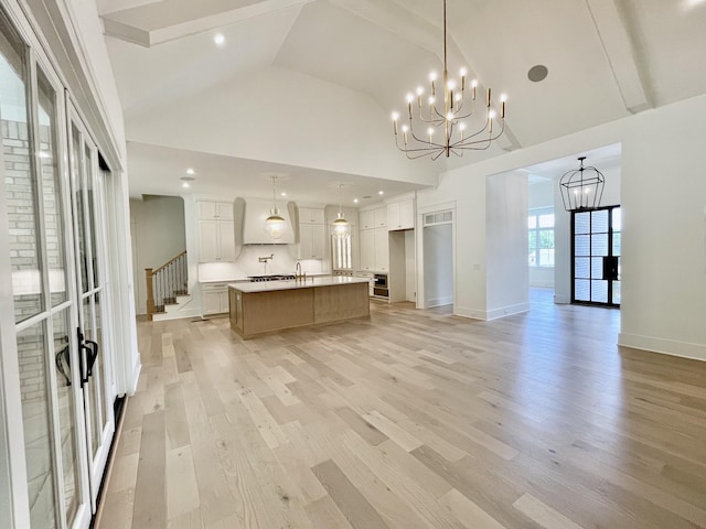 kitchen featuring a large island with sink, white cabinets, and hanging light fixtures