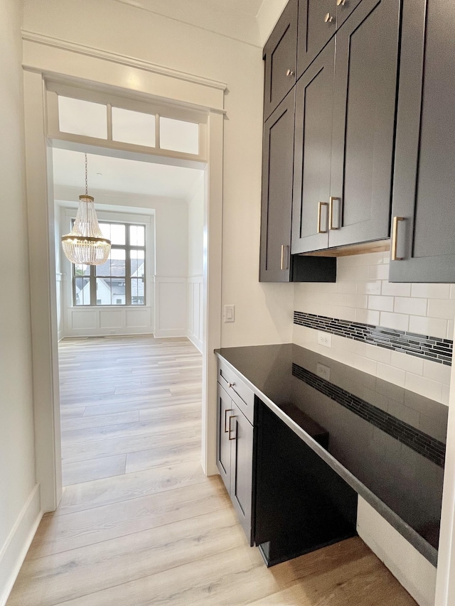 kitchen featuring an inviting chandelier, light hardwood / wood-style flooring, and tasteful backsplash