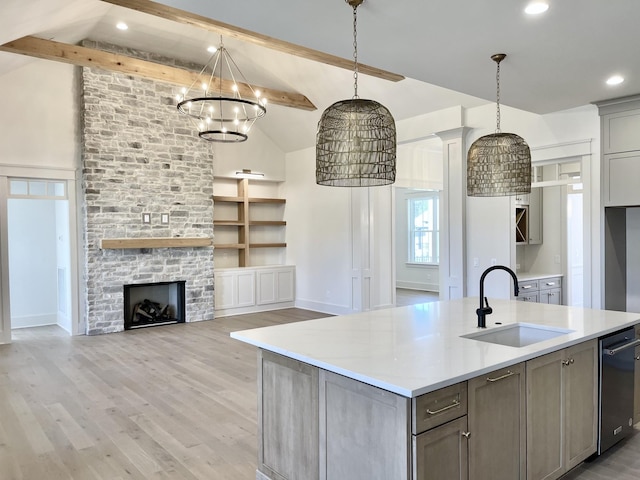 kitchen with sink, an island with sink, dishwasher, and decorative light fixtures