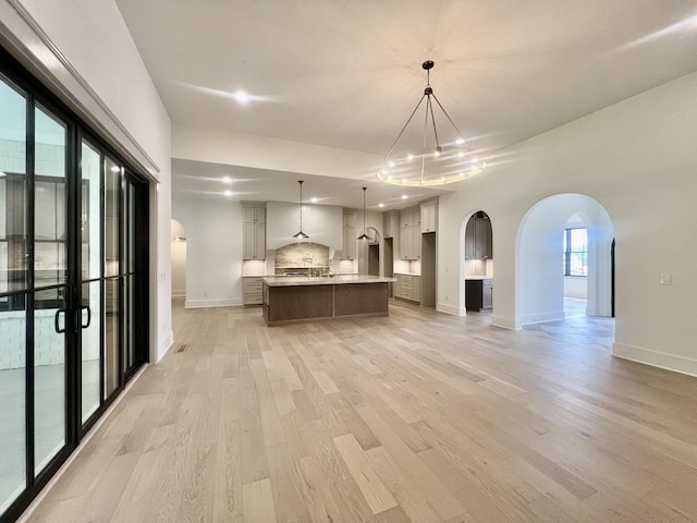 kitchen with black stovetop, hanging light fixtures, light hardwood / wood-style flooring, and a spacious island