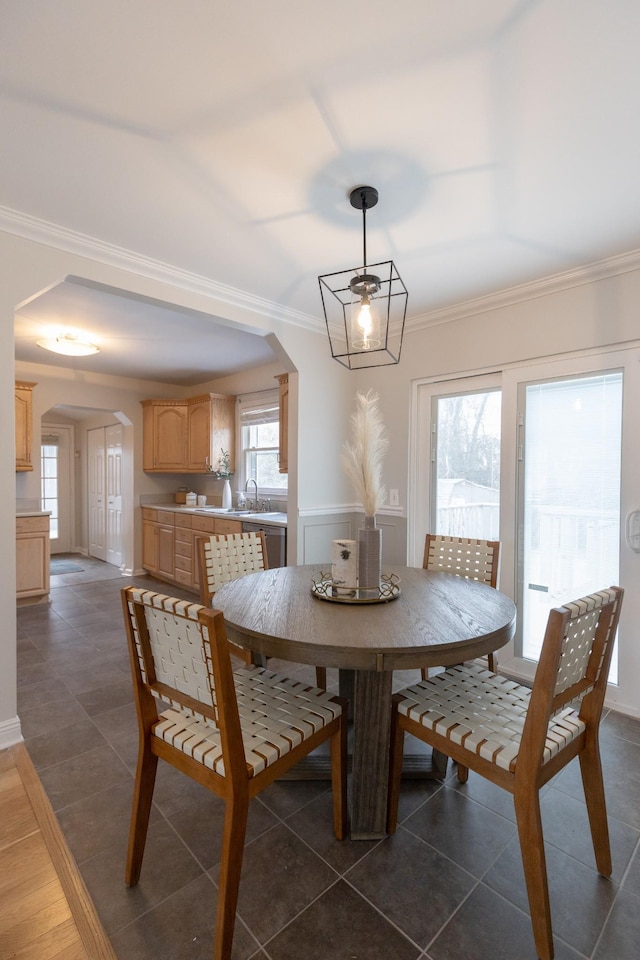 dining room featuring sink, dark tile patterned flooring, and ornamental molding