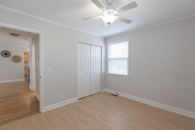 unfurnished bedroom featuring crown molding, light hardwood / wood-style floors, a closet, and ceiling fan