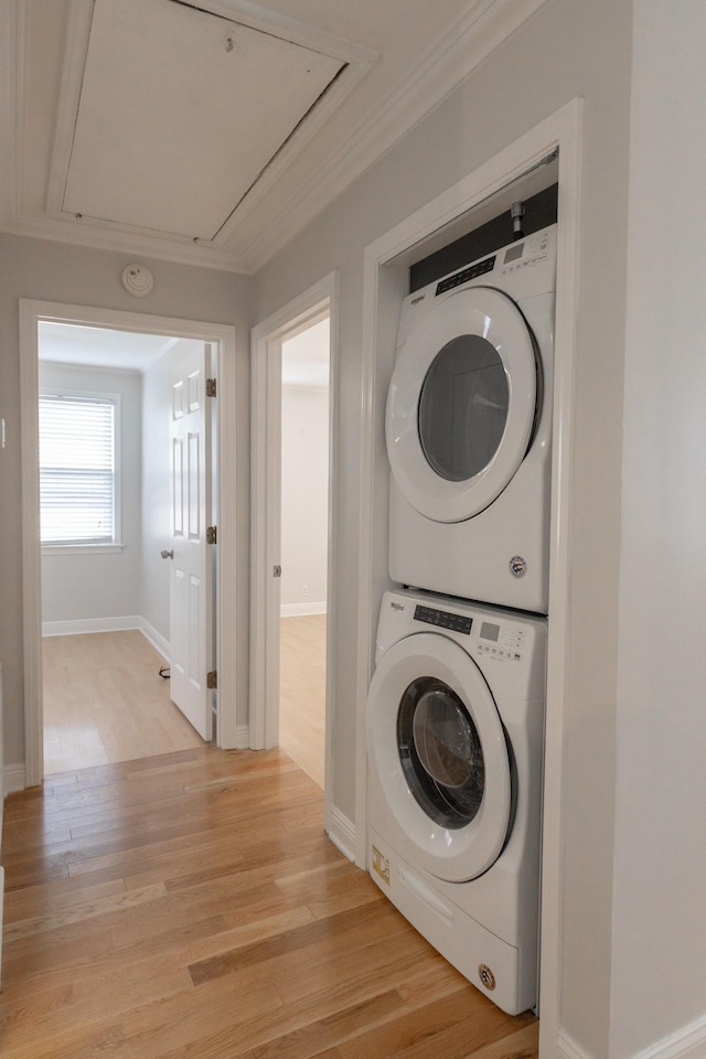 washroom with light hardwood / wood-style floors, stacked washer and clothes dryer, and ornamental molding