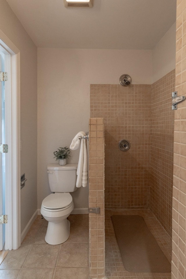 bathroom featuring tiled shower, toilet, and tile patterned flooring