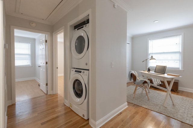 laundry room featuring light hardwood / wood-style floors, ornamental molding, and stacked washing maching and dryer