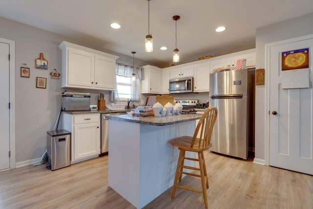 kitchen with a kitchen island, white cabinetry, hanging light fixtures, and stainless steel appliances