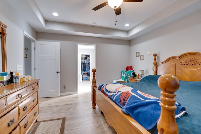 bedroom featuring a spacious closet, a closet, ceiling fan, and light hardwood / wood-style flooring