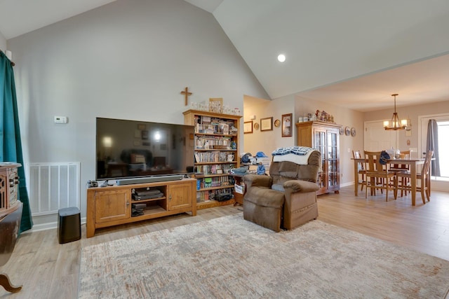 living room with light wood-type flooring, a chandelier, and lofted ceiling