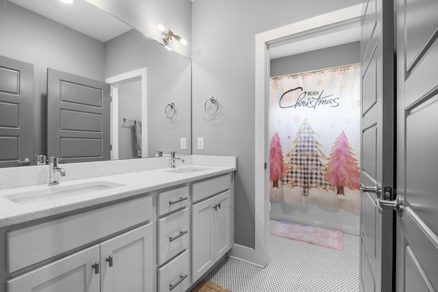 bathroom featuring double vanity, tile patterned flooring, a sink, and baseboards