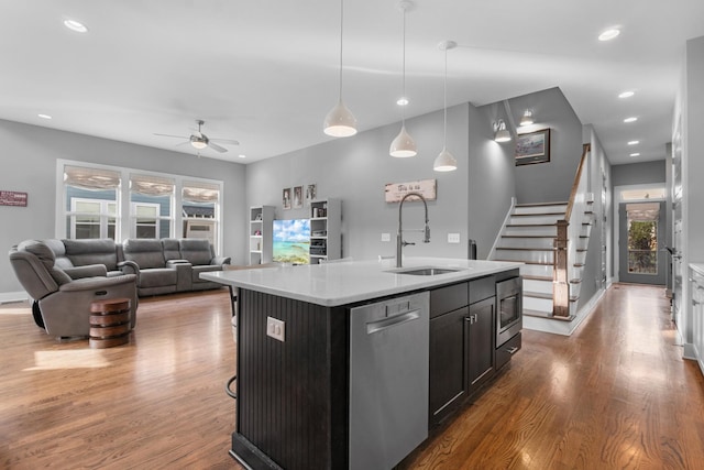 kitchen with a center island with sink, light countertops, appliances with stainless steel finishes, a sink, and wood finished floors