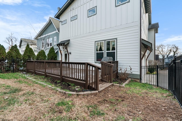 rear view of house with fence, a deck, and board and batten siding