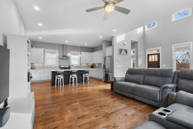 living room with a ceiling fan, recessed lighting, and wood finished floors