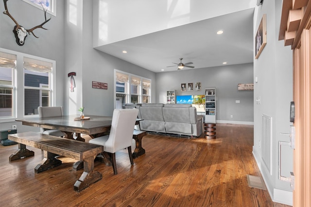 dining room with baseboards, ceiling fan, wood finished floors, a high ceiling, and recessed lighting