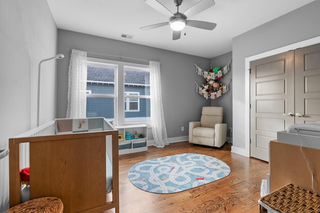 sitting room with ceiling fan, wood finished floors, visible vents, and baseboards