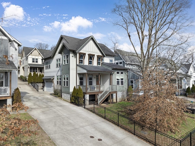 view of front of property with a garage, fence, concrete driveway, a residential view, and board and batten siding