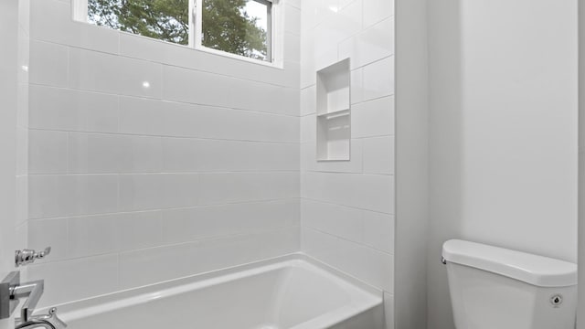 bathroom with toilet and tiled shower / bath