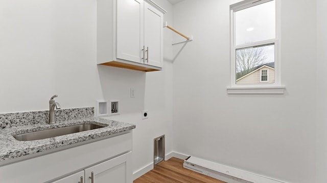 clothes washing area featuring sink, light wood-type flooring, hookup for a washing machine, electric dryer hookup, and cabinets