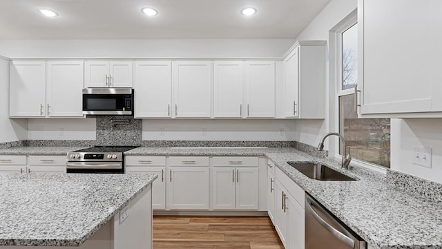 kitchen featuring sink, white cabinets, light stone countertops, and appliances with stainless steel finishes