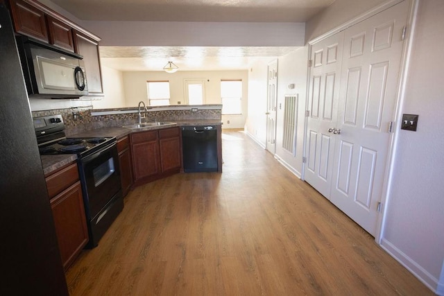 kitchen featuring wood-type flooring, sink, kitchen peninsula, and black appliances