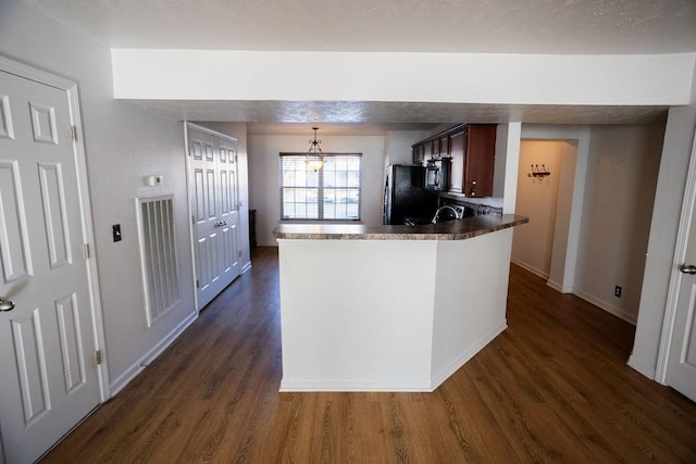 kitchen with dark wood-type flooring, pendant lighting, stainless steel refrigerator, and kitchen peninsula