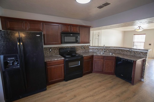 kitchen featuring sink, tasteful backsplash, light wood-type flooring, kitchen peninsula, and black appliances