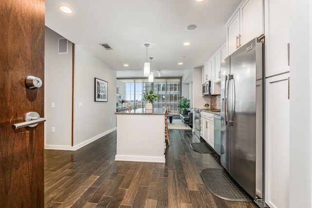 kitchen with pendant lighting, dark hardwood / wood-style flooring, appliances with stainless steel finishes, white cabinetry, and a center island