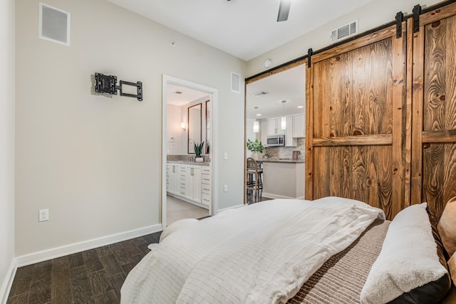 bedroom featuring ceiling fan, ensuite bathroom, and a barn door